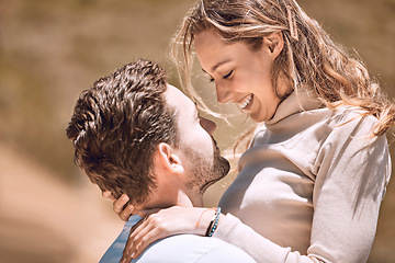 Image showing Loving, affectionate and caring young couple bonding while enjoying the day outdoors in nature. Happy, in love and smiling man embracing his wife while holding her outside on a valley or hill.