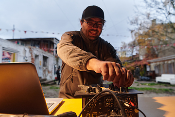 Image showing A young man is entertaining a group of friends in the backyard of his house, becoming their DJ and playing music in a casual outdoor gathering