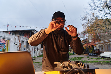 Image showing A young man is entertaining a group of friends in the backyard of his house, becoming their DJ and playing music in a casual outdoor gathering