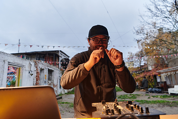 Image showing A young man is entertaining a group of friends in the backyard of his house, becoming their DJ and playing music in a casual outdoor gathering