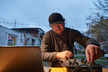 Image showing A young man is entertaining a group of friends in the backyard of his house, becoming their DJ and playing music in a casual outdoor gathering