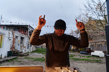 Image showing A young man is entertaining a group of friends in the backyard of his house, becoming their DJ and playing music in a casual outdoor gathering