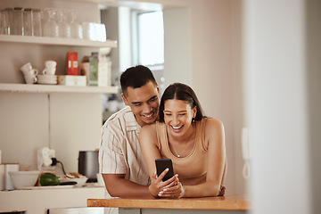 Image showing Happy couple browsing on a phone and laughing at funny social media videos on her phone while relaxing together at home. Carefree, smiling and young boyfriend hugging his girlfriend in the kitchen