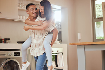 Image showing Happy, playful and excited couple playing in the kitchen at home and the boyfriend giving a piggyback ride to his girlfriend. Carefree and joyful lovers having fun together and enjoying the weekend