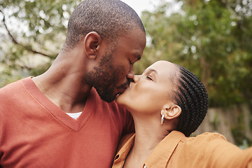 Image showing Romantic, in love and young couple kissing and taking a selfie outdoors in nature on a picnic. Happy, loving and African partners taking a picture while spending quality time together in a garden.