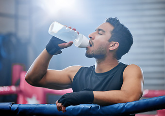 Image showing Fit, active and healthy boxer drinking water, on break and staying hydrated in routine workout, training or boxing ring exercise. Sporty, athletic or strong man after kickboxing fight or sports match