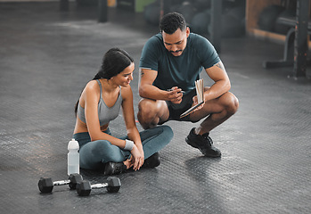 Image showing Personal trainer, coach or fitness instructor helping an active and fit woman in the gym. Young female athlete sitting down and managing her workout routine or schedule with her exercising partner