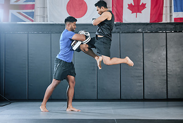 Image showing Healthy professional coach sparring and training male kickboxer indoors. Practice sports, exercise and fitness. Two muscular men fighting, jumping and blocking kicks with discipline in class.