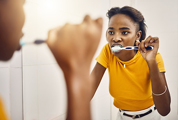 Image showing Brushing teeth, dental hygiene and oral care with a young woman looking at her reflection in the bathroom mirror at home. Maintaining mouth, teeth and gum health with a daily toothcare routine