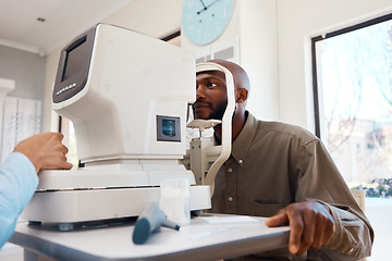 Image showing Young African man getting an eye exam by an optometrist with technical optic equipment. Male getting an eyesight test with a autorefractor to get eyewear. Guy at an optical shop for new spectacles.