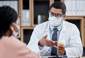 Image showing Medical appointment or doctor consulting a patient during the covid pandemic from his office. Male GP helping a sick client by giving her tablets, medication or medicine and wearing a face mask