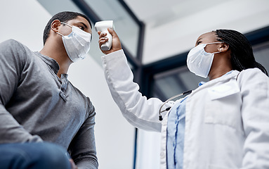 Image showing Female doctor consulting a male covid patient, taking his temperature with infrared thermometer in hospital room or clinic. Man wearing mask and health care professional pointing medical equipment.