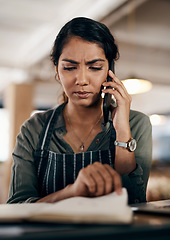 Image showing Young and confused business owner on the phone making a stock order for her cafe, restaurant or coffee shop. A female employee, manager or store owner looking at a book of products or inventory.