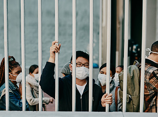 Image showing Behind bars, lockdown and covid restrictions with a man wearing a mask during a pandemic and travel ban. Portrait of a male being locked out during the international or global corona virus outbreak