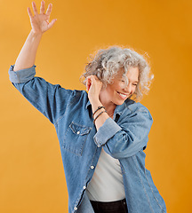 Image showing Celebrating, partying and dancing mature woman, happy and cheerful senior making waving hand gesture and smiling. Elderly caucasian woman having fun while she dances against an orange background
