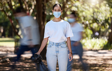 Image showing Woman in covid face mask cleaning the park for clean, hygiene and safe green environment. Responsible activist, volunteer or community service worker with rubbish, trash and garbage in a plastic bag