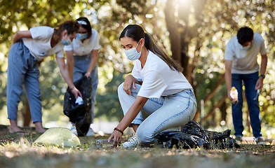 Image showing Group of volunteers picking up, cleaning and reducing pollution in a public nature park together. Diverse community wearing face masks to protect from disease, collecting dirt and doing cleanup