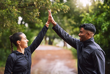 Image showing Athletic couple high five while exercising in a park or forest, celebrating and winning before a run. Fit boyfriend and girlfriend bonding while keeping fit and healthy. Fun lovers being active