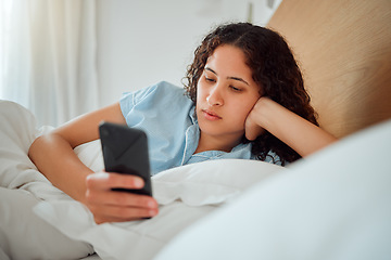Image showing Young woman checking phone and social media in bed, browsing internet after waking up to text message at home. Female relaxing, chatting online and streaming. Lady feeling lazy on the weekend