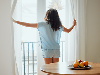 Image showing Awake, waking up and fresh new day or morning for a young woman opening the curtains. Back view of a carefree female with hope thinking while looking out the window in her house or at home