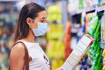 Image showing Woman reading food box information or list at the grocery store, shop or supermarket. Trendy, young female shopping in covid pandemic with a mask for organic, fresh and healthy ingredients.