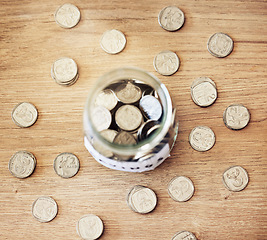 Image showing . Savings, investment and a jar full of coins on a wooden table for future financial growth or insurance. Overhead view of an overflowing container with money for a donation or retirement fund.