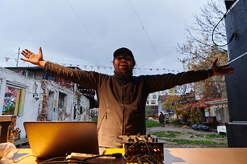 Image showing A young man is entertaining a group of friends in the backyard of his house, becoming their DJ and playing music in a casual outdoor gathering