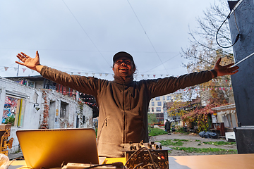 Image showing A young man is entertaining a group of friends in the backyard of his house, becoming their DJ and playing music in a casual outdoor gathering