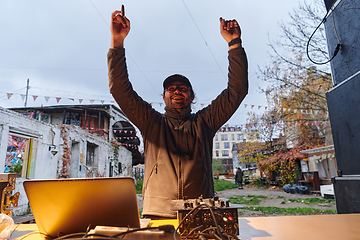 Image showing A young man is entertaining a group of friends in the backyard of his house, becoming their DJ and playing music in a casual outdoor gathering