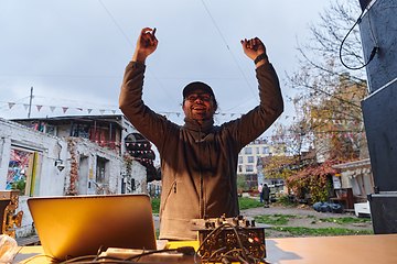 Image showing A young man is entertaining a group of friends in the backyard of his house, becoming their DJ and playing music in a casual outdoor gathering