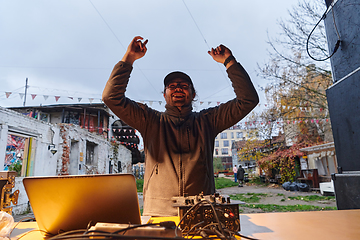 Image showing A young man is entertaining a group of friends in the backyard of his house, becoming their DJ and playing music in a casual outdoor gathering