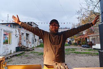 Image showing A young man is entertaining a group of friends in the backyard of his house, becoming their DJ and playing music in a casual outdoor gathering