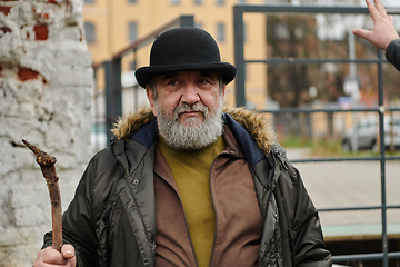 Image showing An elderly man with a beard and a worn hat passionately imparts traditional values and cultural wisdom to others, embodying the essence of heritage preservation and storytelling.