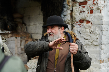 Image showing An elderly man with a beard and a worn hat passionately imparts traditional values and cultural wisdom to others, embodying the essence of heritage preservation and storytelling.