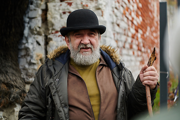 Image showing An elderly man with a beard and a worn hat passionately imparts traditional values and cultural wisdom to others, embodying the essence of heritage preservation and storytelling.