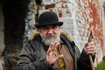 Image showing An elderly man with a beard and a worn hat passionately imparts traditional values and cultural wisdom to others, embodying the essence of heritage preservation and storytelling.