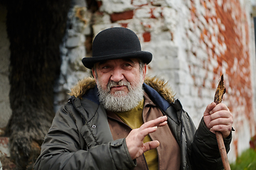 Image showing An elderly man with a beard and a worn hat passionately imparts traditional values and cultural wisdom to others, embodying the essence of heritage preservation and storytelling.