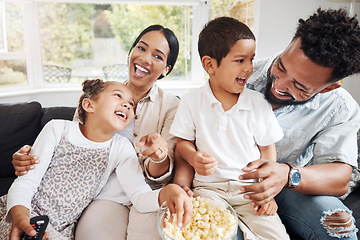 Image showing Family watching tv or a movie, having fun and eating popcorn together at home. Love and laughter with affectionate parents and happy children smiling, enjoying the weekend and feeling carefree