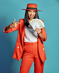 Image showing Rich woman showing off wealth, going on shopping spree and winning the lottery standing against blue studio background. Portrait of a stylish, trendy and happy female millionaire holding a cash prize