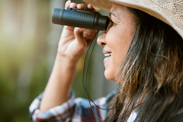 Image showing . Nature, animal and bird watching of a smiling older woman looking and holding binoculars outside. Closeup of a mature female enjoying retirement relaxing on a day outdoors break feeling carefree.