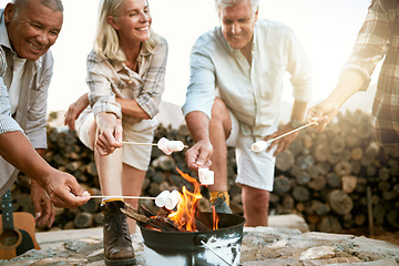 Image showing Camping, hiking and adventure senior people melting marshmallows in a camp fire during a nature retreat or getaway outdoors. Happy retired or senior group of friends enjoying fun recreation activity