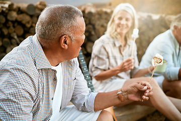 Image showing . Toasting marshmallows, camping and adventure with a senior man and his retired friends sitting outside. Holiday, vacation and getaway with mature people eating and enjoying time together outdoors.