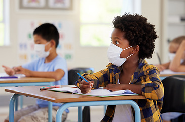 Image showing Covid, education and learning with a student in class, writing and studying at a school while wearing a mask for safety. Young boy sitting in a classroom, listening to the lesson and taking notes