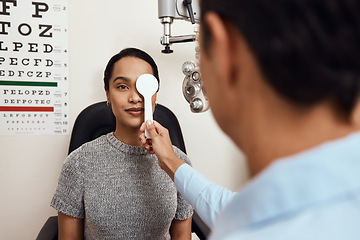 Image showing Eye exam, vision testing at an optometrist with young woman and doctor. Opthamologist using an occluder to test eyesight before being fitted with glasses. Relaxed lady smiling, satisfied with service