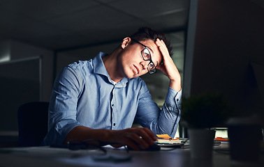 Image showing Tired, stressed businessman suffering from headache, working late night in the office. Serious, frustrated and overworked corporate male with headache staring at his screen in the dark.