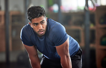 Image showing Tired, breathing and fitness gym man taking a break from workout, training or exercising inside a wellness center. Young athletic, masculine guy resting after his strength or muscle exercise session