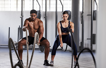 Image showing Active, fitness partners training together, exercising with battle ropes in gym. Athletic sports couple in motion doing arms and cardio workout in wellness center for strength and healthy lifestyle.