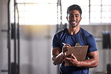 Image showing Gym, workout and personal trainer with clipboard consulting at a training sports in gym. Portrait of muscular, active and smiling fitness coach writing on health, wellness and exercise with flare