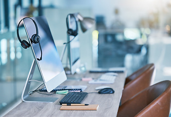 Image showing Headphone or headset in an empty call center office with computer monitor display for online customer service or support. Helpdesk hotline assistance gadgets and crm equipment in workplace or station