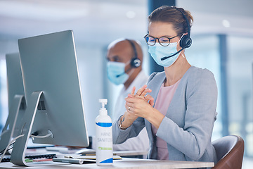 Image showing Covid, hand sanitizer and call center agent with mask cleaning hands, protecting or staying safe in customer support office. Receptionist, advisor or operator with computer preventing spread of virus